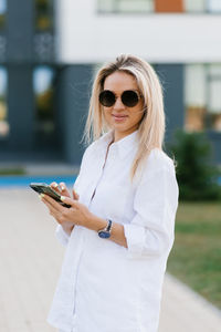 Young attractive woman in a white suit walking through the streets of the city on a sunny day