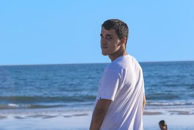 Portrait of man standing at beach against clear sky