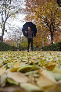 Man with umbrella standing on field during autumn