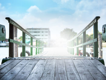 Empty bench on boardwalk against sky