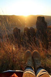 Low section of person standing on land against sky during sunrise