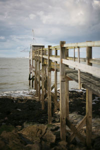 Wooden pier on beach against sky