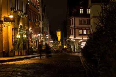 Illuminated street amidst buildings at night