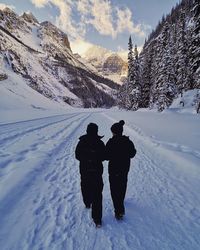 Rear view of people on snowcapped mountain against sky