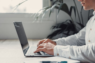 Midsection of man using laptop at home