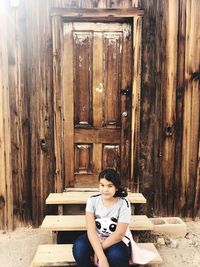 Portrait of woman sitting on wooden door