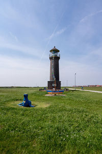 Lighthouse on field against sky