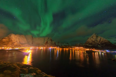 Scenic view of sea by illuminated mountain against sky at night