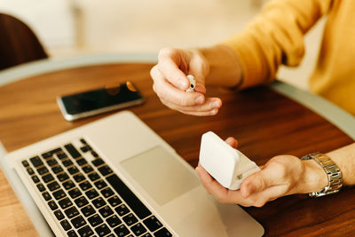 Midsection of woman using smart phone on table