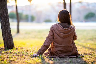 Rear view of woman sitting on land