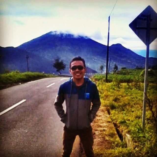 lifestyles, mountain, young adult, casual clothing, leisure activity, looking at camera, standing, portrait, sky, front view, road, transportation, person, young men, mountain range, landscape, the way forward, full length