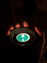 Close-up of hand holding lit candle