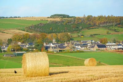 Scenic view of farm and houses against sky