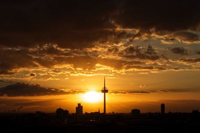 Silhouette buildings against cloudy sky during sunset