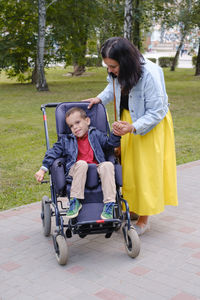 Family with cerebral palsy child on special wheelchair walking outdoors. integration and