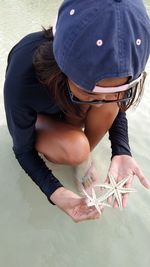 High angle view of woman holding starfishes at beach