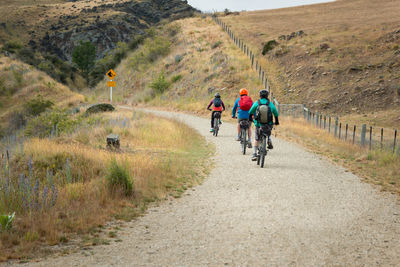 Rear view of people riding bicycle on road