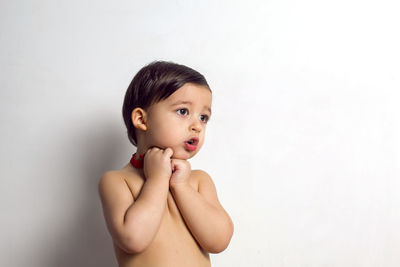 Child without a t-shirt sitting on a white background with a red bow tie