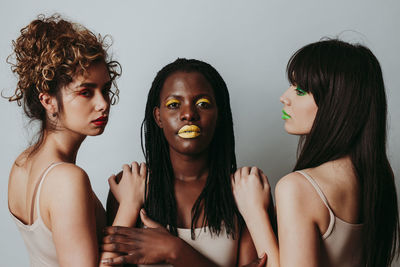 Beautiful young women with make up embracing against gray background