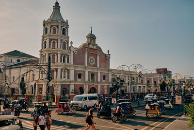 People on street by buildings against sky in city