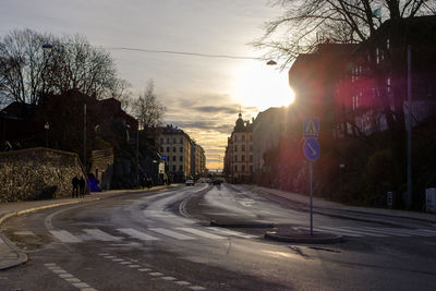 Street in city against sky at sunset