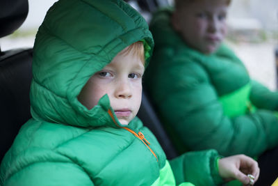 Portrait of boy wearing hooded jacket while sitting in car