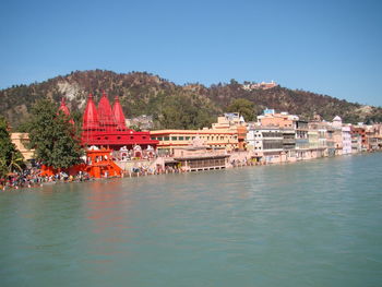 Scenic view of sea by buildings against clear blue sky