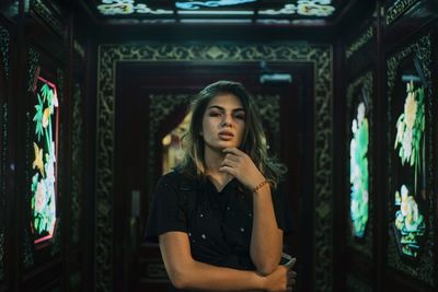 Portrait of young woman standing against wall