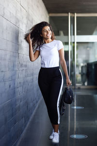 Portrait of smiling woman standing against wall