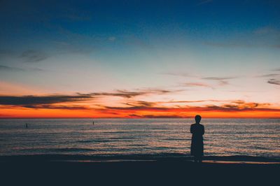 Silhouette man looking at sea against sky during sunset