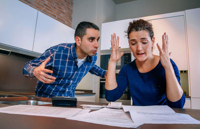 Young couple looking away while sitting on table