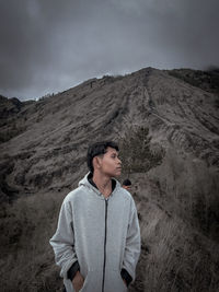 Young man standing on mountain against sky