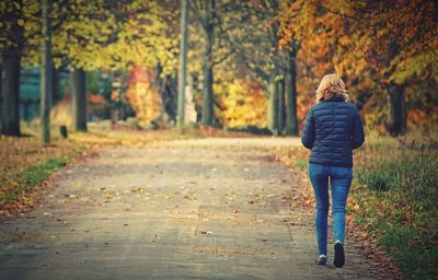 Rear view of woman walking on street during autumn