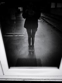 Low section of woman standing in illuminated tunnel