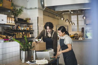 Male owner discussing with female employee over juice bottle at store