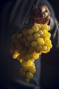 Close-up of hand holding grapes over black background