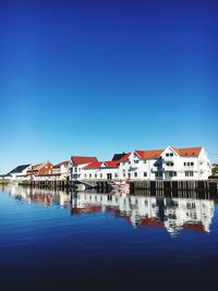 Buildings by lake against blue sky