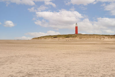 Lighthouse on beach against sky