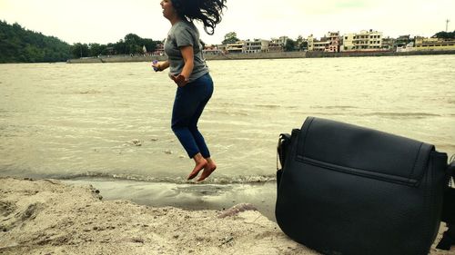 Full length of young woman jumping on beach