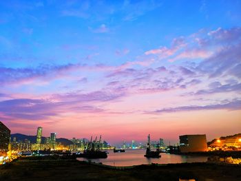 Illuminated city against sky at sunset