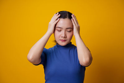Mid adult man standing against yellow background