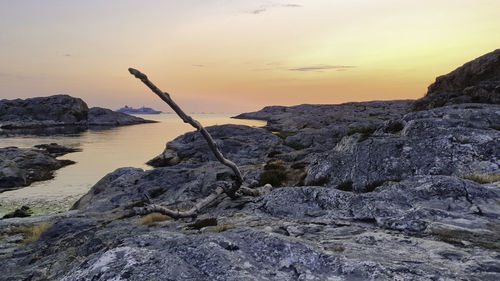 Rock formation on beach against sky during sunset
