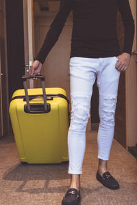 Low section of man with suitcase standing on floor