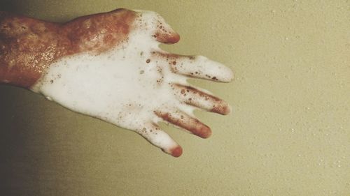 Close-up of human hand against colored background