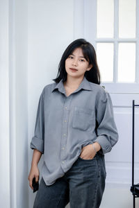 Portrait of young woman standing against wall