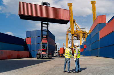 Engineers are overseeing the transportation of cargo with containers inside the warehouse.