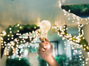 Close-up of hand holding illuminated christmas lights