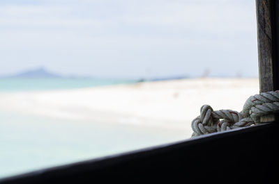 Cropped image of rope on window at beach