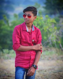 Young man wearing sunglasses standing on land