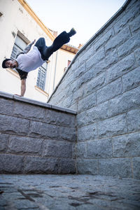 Low angle view of man performing stunt on wall